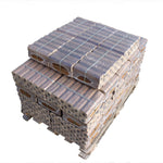 A stack of oak Pini-Kay heat logs bound together with a rubber band, tightly compressed.