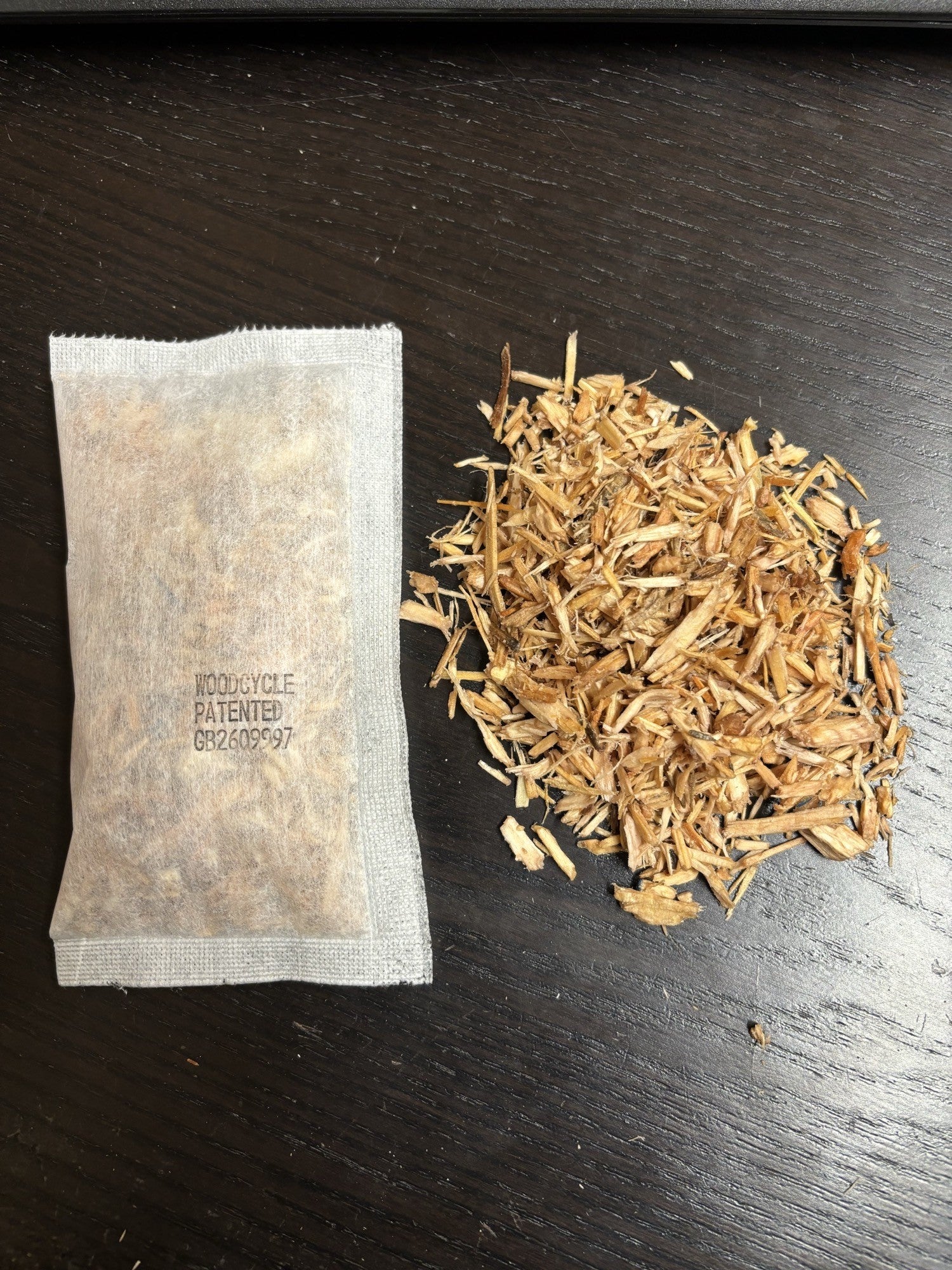 Woodcycle natural tea bag firelighter and loose on a dark surface