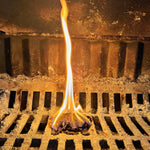 Woodcycle Firelighter Tea Bag burning on a metal grate with a dark background